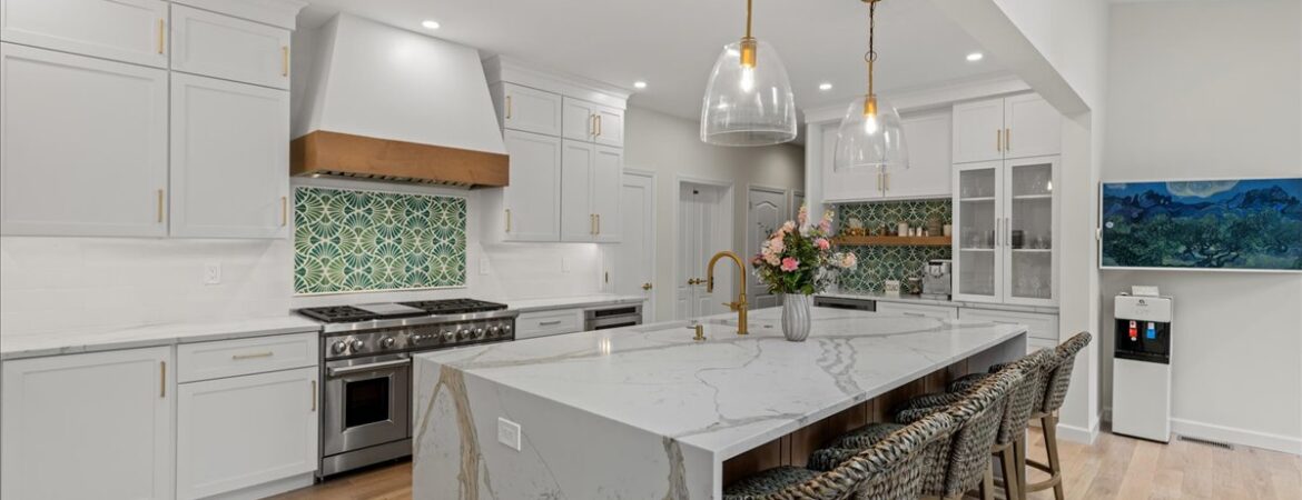 Bright modern kitchen with white cabinets, marble island, and stylish lights, ideal for home renovation.