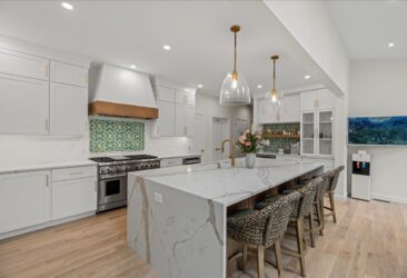 Bright modern kitchen with white cabinets, marble island, and stylish lights, ideal for home renovation.