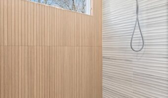 Modern bathroom shower with wood paneling and large window, featuring sleek design and natural light.