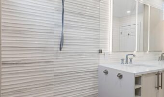 Modern bathroom with textured wall tiles, showerhead, and sleek vanity for home renovation projects.