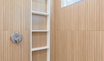 Modern wooden shower with ladder-style towel rack and large window.