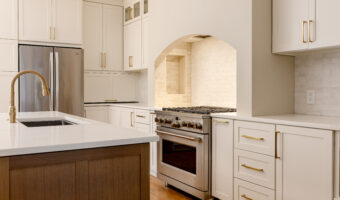 Modern white kitchen with gold hardware, stainless steel appliances, and a central island for home r.