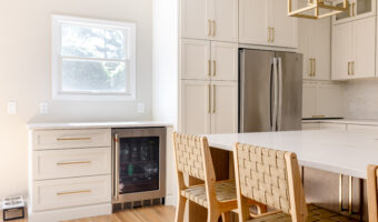 Bright modern kitchen with white cabinets, stainless steel refrigerator, and a cozy dining area with.