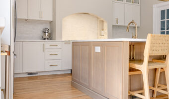 Bright modern kitchen with white cabinets, wooden island, and gold fixtures, showcasing professional.