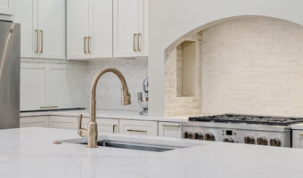 Modern kitchen with white cabinetry, marble countertops, and stylish lighting fixtures for home reno.