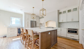 Modern kitchen with white cabinets, a central island with seating, and stainless steel appliances, p.