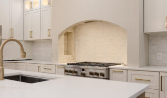 Modern white kitchen with gold accents, built-in appliances, and a spacious countertop for renovatio.