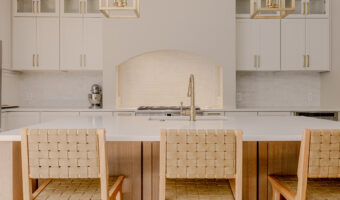 Bright modern kitchen with white cabinets, marble countertops, and woven bar stools for stylish home.