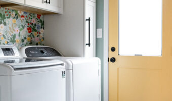 Modern laundry room with white cabinets and yellow door, stylish and functional design.