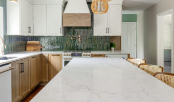 Bright modern kitchen with white cabinets, green backsplash, and marble island for stylish home reno.