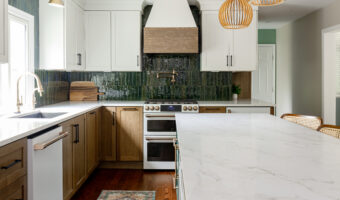 Modern kitchen with white and wood cabinetry, marble island, and stylish pendant lighting.