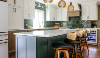 Bright modern kitchen with white cabinets, green backsplash, and wooden accents, featuring a central.