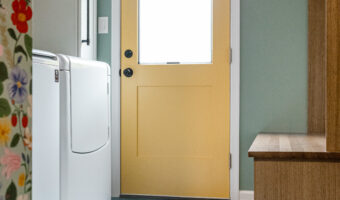 Bright yellow door in a modern kitchen with pastel green walls and floral wallpaper.