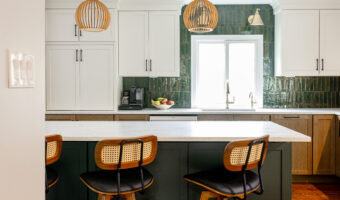 A modern kitchen with white cabinets, green tiled backsplash, and a central island with three bar st.
